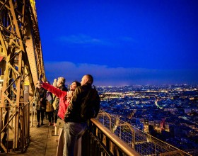 Una pareja tomándose una foto con copas de champán en el segundo piso de la Torre Eiffel