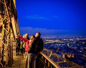 Una pareja tomándose una foto con copas de champán en el segundo piso de la Torre Eiffel